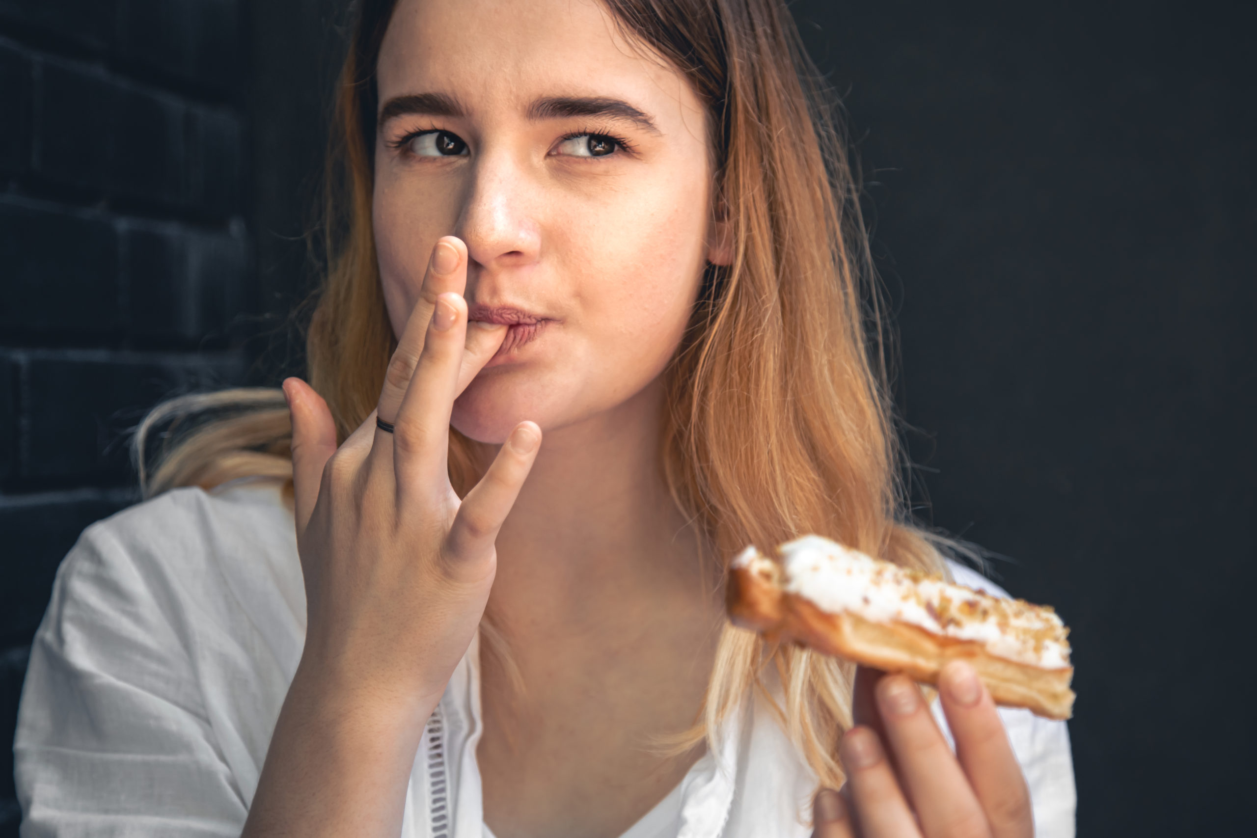 A young woman eats an appetizing eclair cake, close up. Flavor